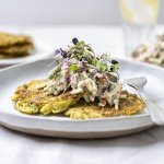Er liggen 3 klaargemaakte rösti of aardappelkoekjes op het bord.  Ze worden gecombineerd met een appelsalsa en scheutjes groen. 