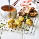Op een barbecuerooster liggen de aardappelen te pronken. Ze zijn afgewerkt met een takje rozemarijn erin geprikt. Er ligt een stukje vlees langs en de paprikasaus zit in een sauskommetje, heerlijk oranje-rood. 