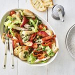 Op tafel staat een grote slakom met hierin de klaargemaakte panzanella op basis van geroosterde paprika, nectarine en gerookte makreel. 