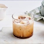 Op tafel staan twee glazen gevuld met de special coffee. Hij is niet omgeroerd, dus de melk laat wolken achter in de zwarte koffie. 