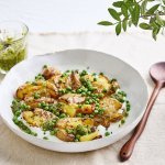 Een heerlijk bordje gevuld met plattekaas met hierop de de krokante 'platgestampte' aardappelen. De groene erwtjes en toefjes pesto zorgen voor een mooie kleur in het bordje.
