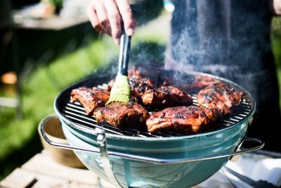 Ribbetjes op een barbecue in de tuin. De kok borstel nog wat marinade op het vlees.